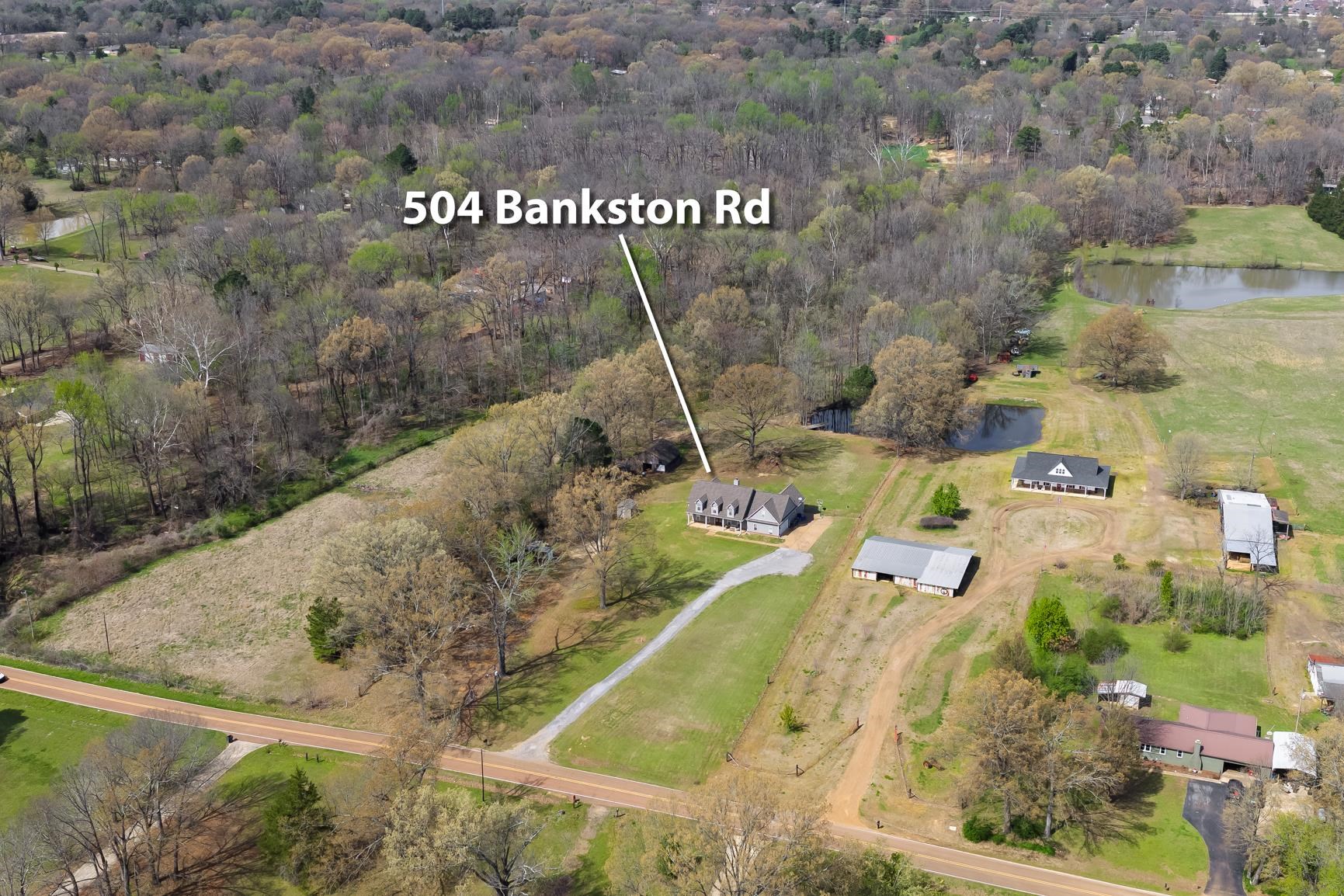504 Bankston Road Nesbit, MS 38651 - Photo 32 of 39 Expansive property featuring a central residence, multiple accessory structures, two visible ponds, and a gravel driveway