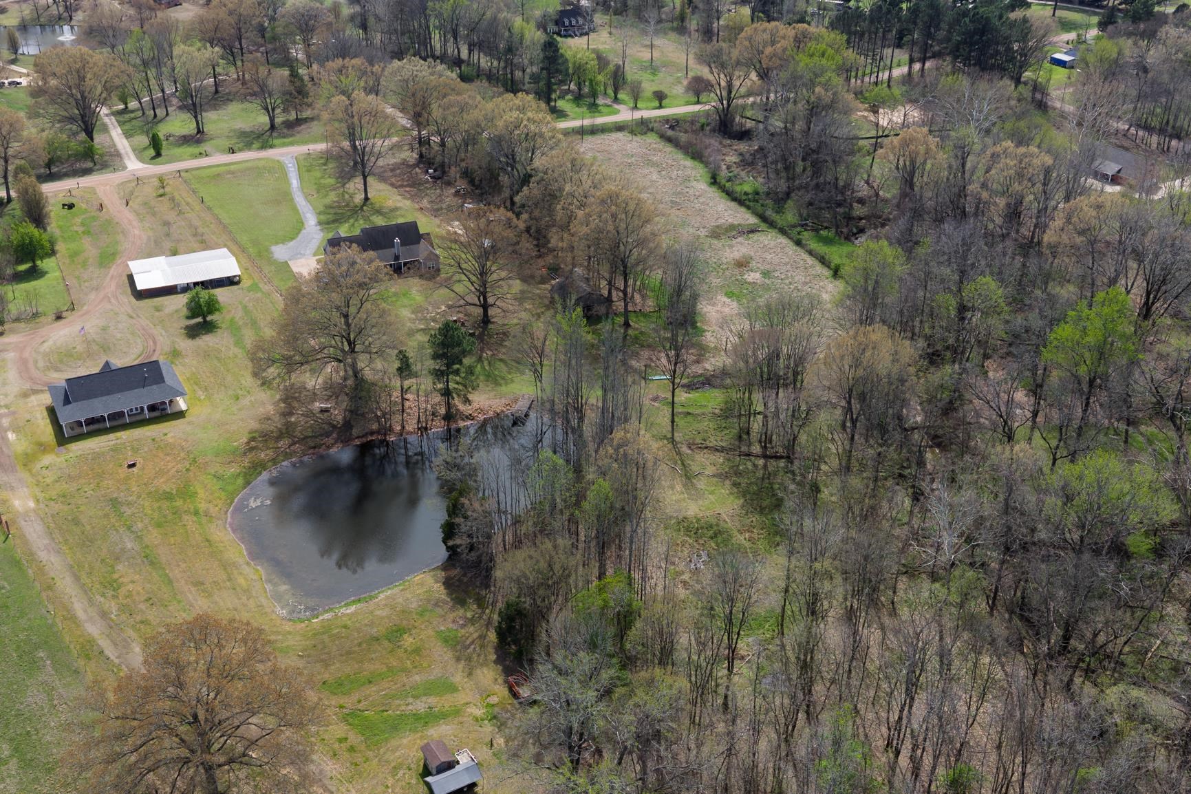 504 Bankston Road Nesbit, MS 38651 - Photo 33 of 39 Expansive property featuring a private pond, two residential structures, a large outbuilding, and mature trees throughout
