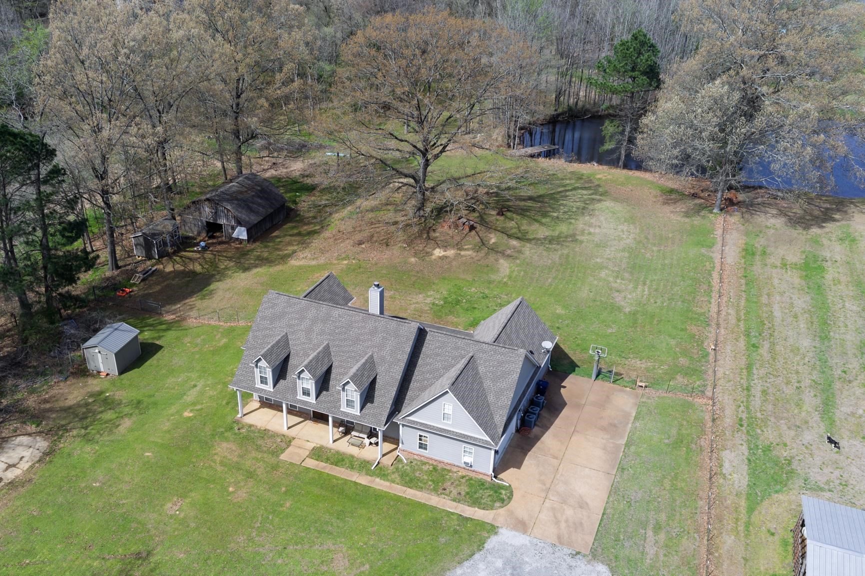 504 Bankston Road Nesbit, MS 38651 - Photo 35 of 39 Expansive property featuring a gray-sided residence with multiple dormers, a covered front porch, and an attached concrete driveway