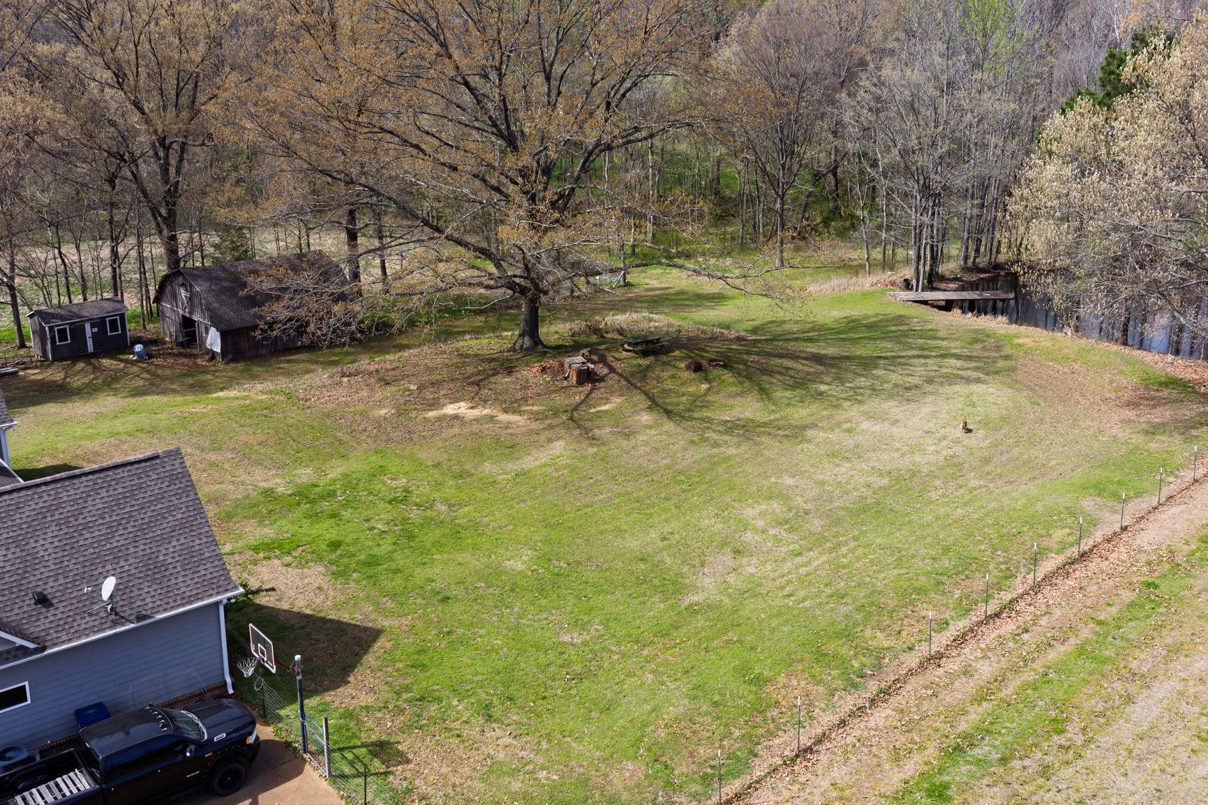 504 Bankston Road Nesbit, MS 38651 - Photo 38 of 39 Expansive green space featuring a large mature tree, a wooden dock over water, and a rustic barn structure