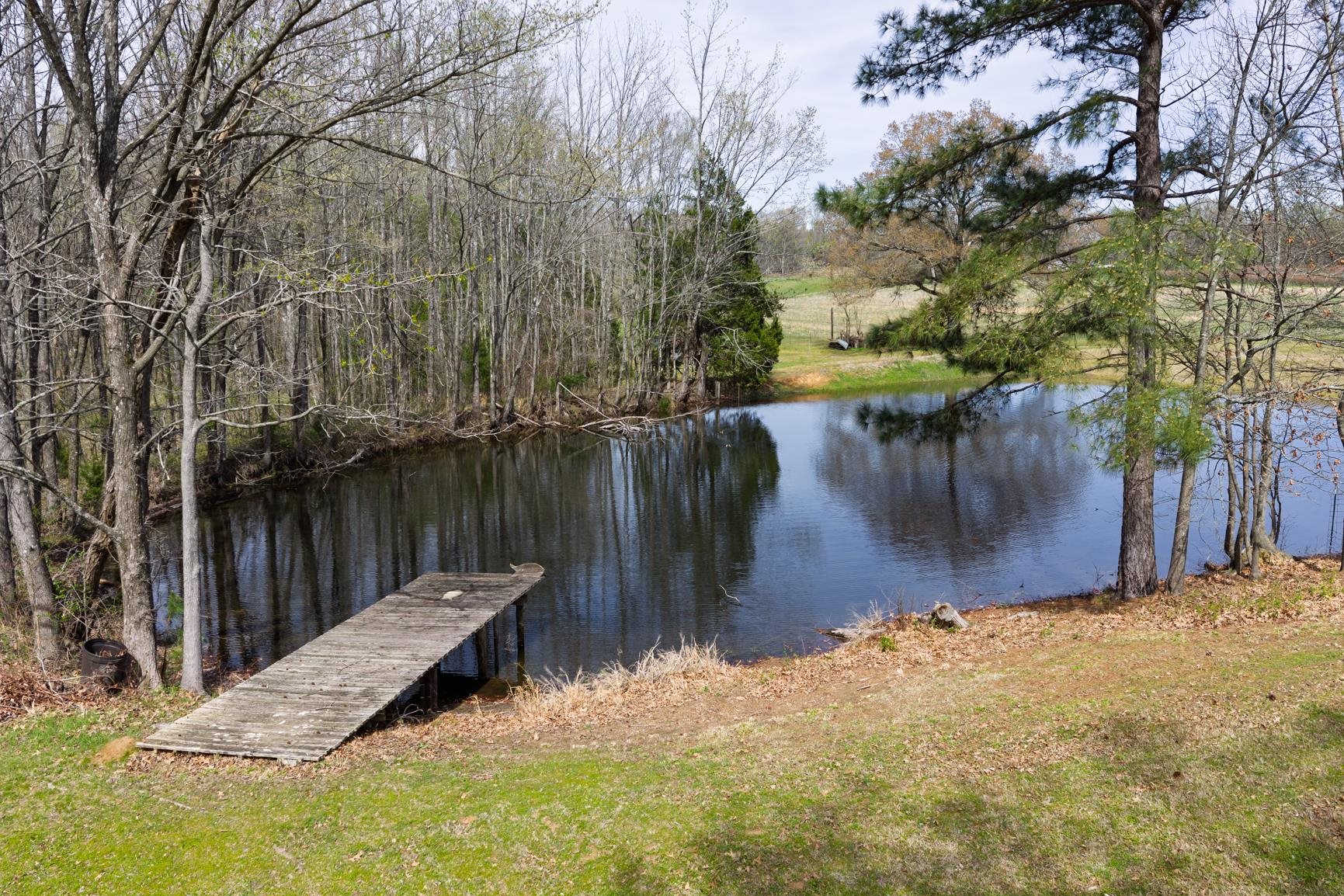 504 Bankston Road Nesbit, MS 38651 - Photo 39 of 39 Private pond with a wooden dock, surrounded by mature trees and a grassy embankment