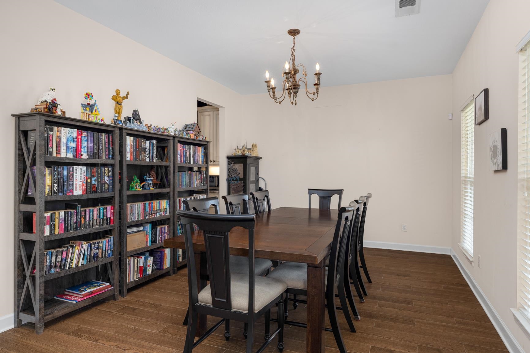 504 Bankston Road Nesbit, MS 38651 - Photo 7 of 39 Dining area featuring wood-finish flooring, a traditional chandelier, multiple windows with blinds, and light-toned wall finishes