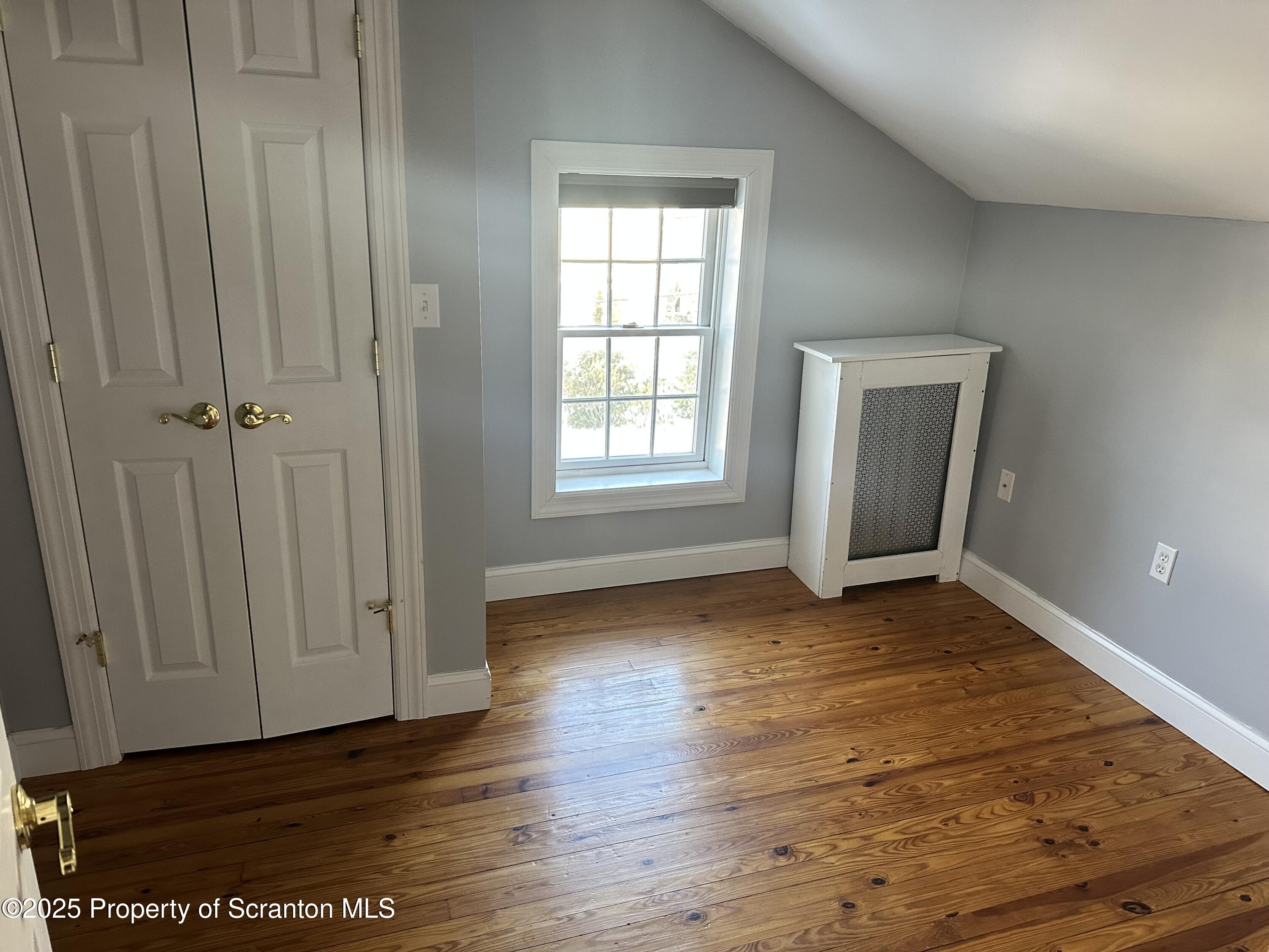 1108 North Abington Road Waverly, PA 18471 - Photo 13 of 32 a view of an empty room with wooden floor and a window