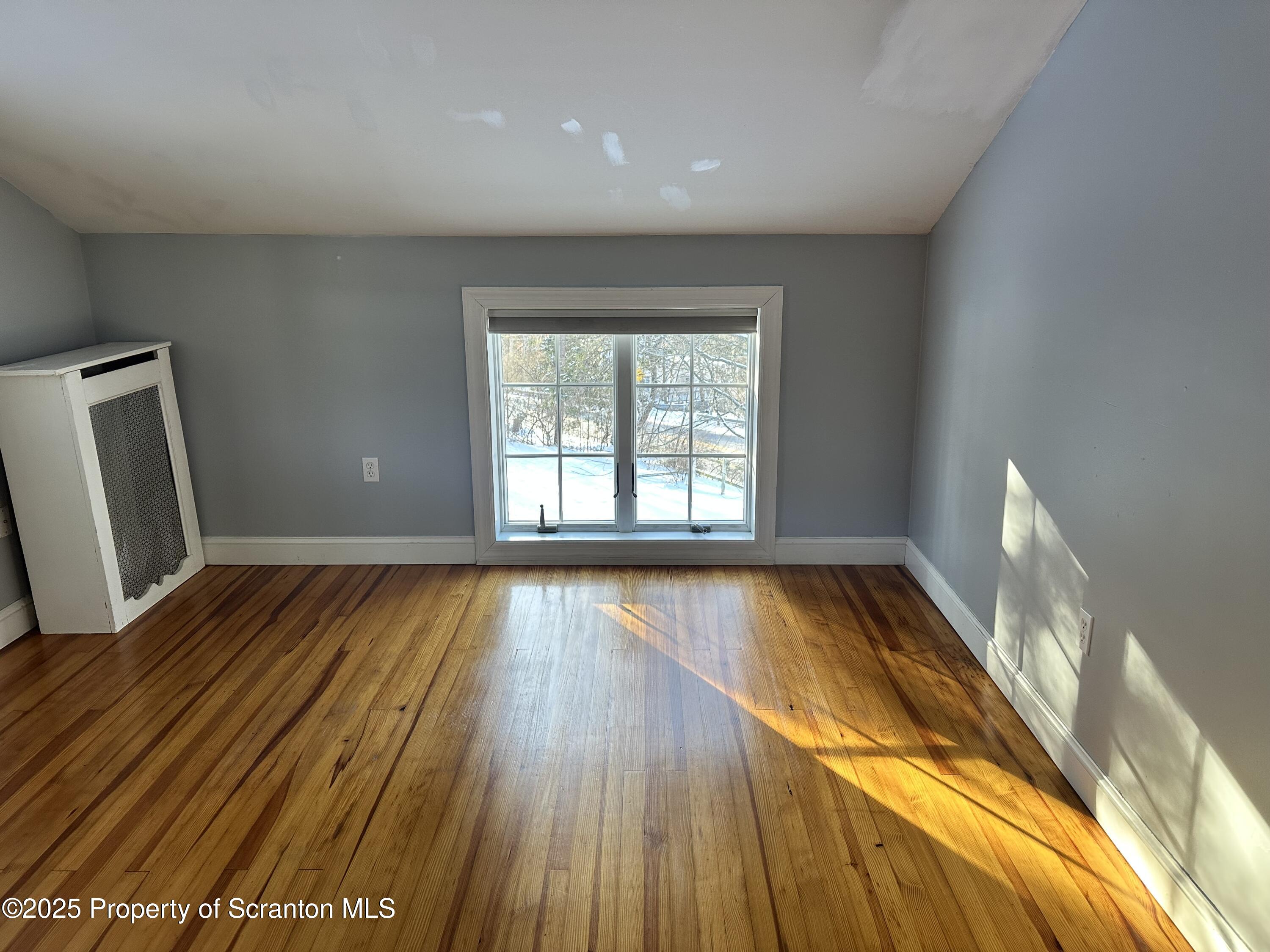 1108 North Abington Road Waverly, PA 18471 - Photo 16 of 32 a view of an empty room with wooden floor and a window
