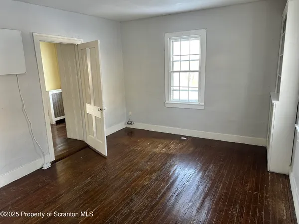 a view of empty room with wooden floor and windows