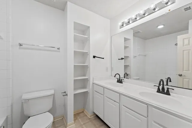 a bathroom with a toilet a sink a mirror and vanity