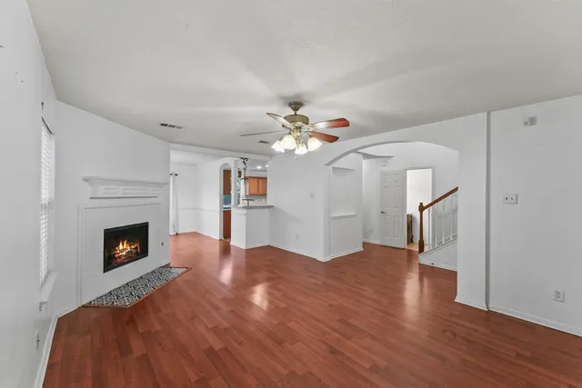 a view of an empty room with wooden floor fireplace and a window