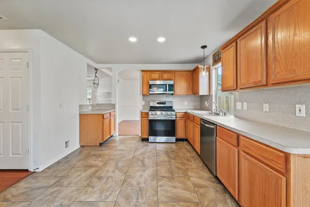 a large kitchen with stainless steel appliances granite countertop a stove a sink and a refrigerator
