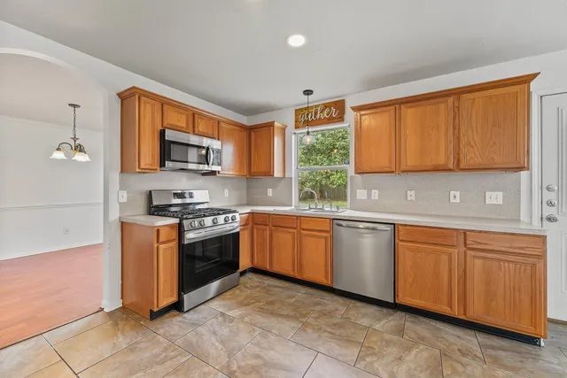 a kitchen with stainless steel appliances granite countertop a stove top oven a sink dishwasher and a microwave oven on the blue kitchen countertops
