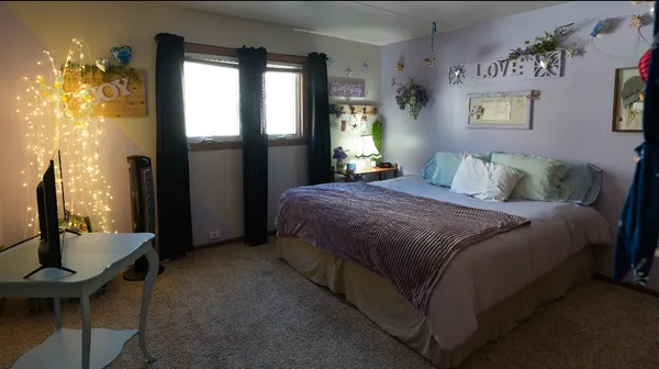 a bedroom with a bed table closet and a flat tv screen