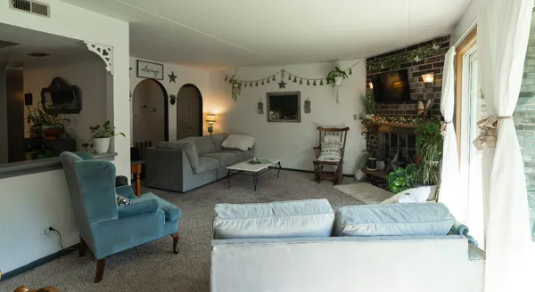 a living room with furniture a flat screen tv and floor to ceiling window