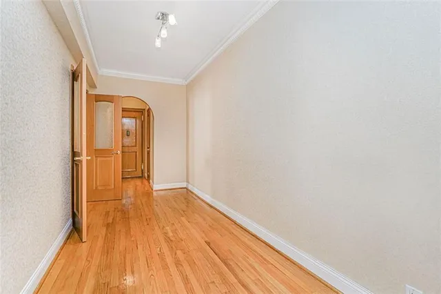 a view of empty room with wooden floor and fan