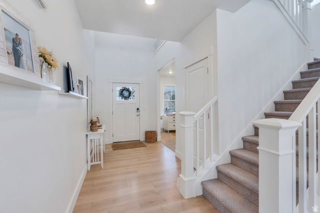 2664 West Maple Street Mapleton, UT 84664 - Photo 10 of 49 Entryway featuring a staircase with carpeted treads and white newel posts, wood-finish flooring, and a white paneled door with glass insert