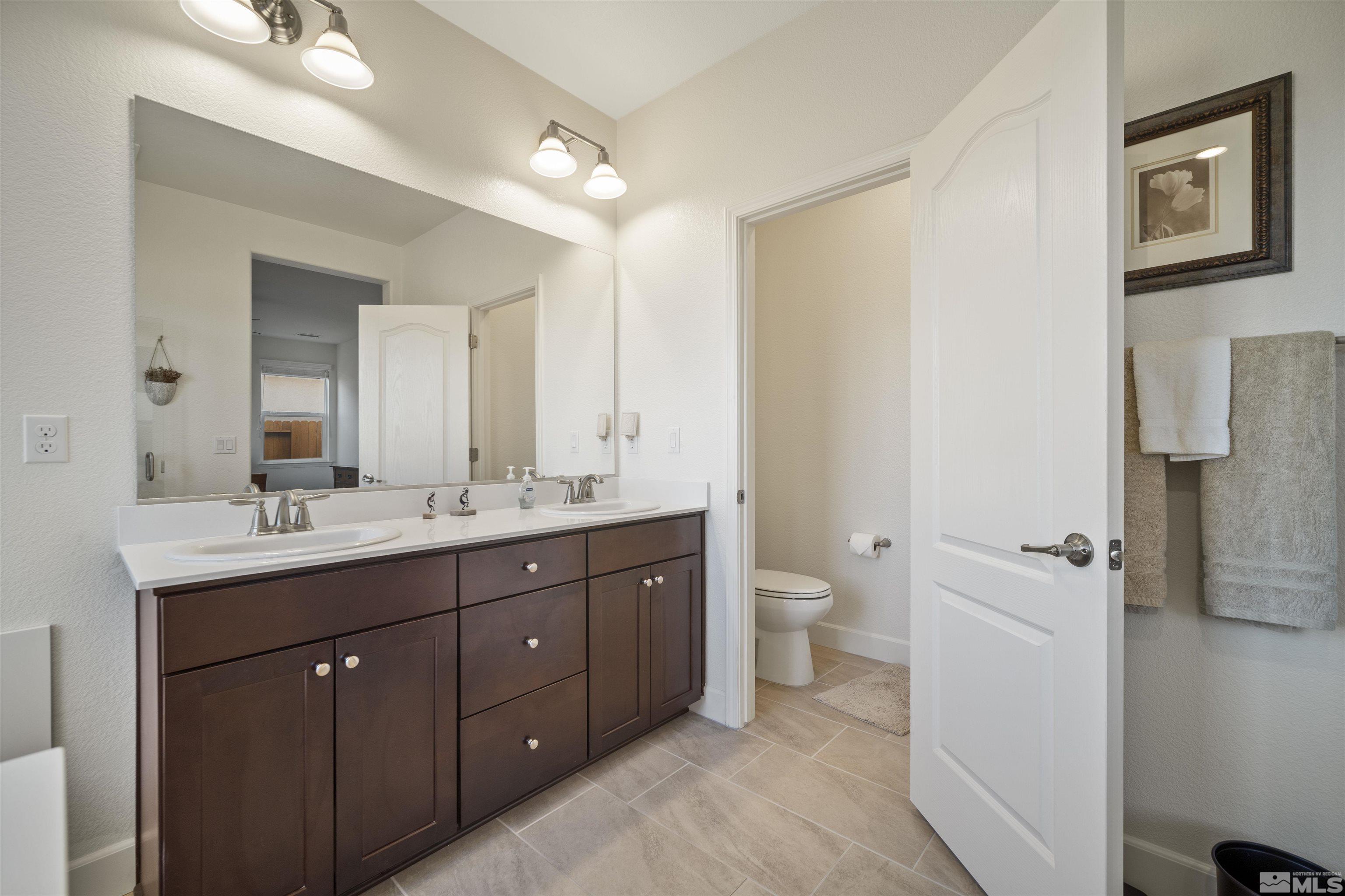 6713 Eagle Peak Drive Carson City, NV 89701 - Photo 24 of 40 a bathroom with a double vanity sink toilet and a mirror