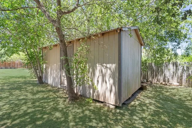 a view of backyard with wooden fence and a large tree