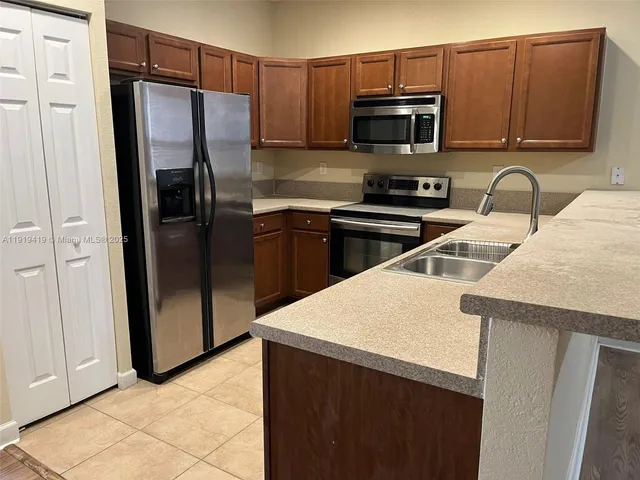 a kitchen with a sink a microwave a refrigerator and cabinets