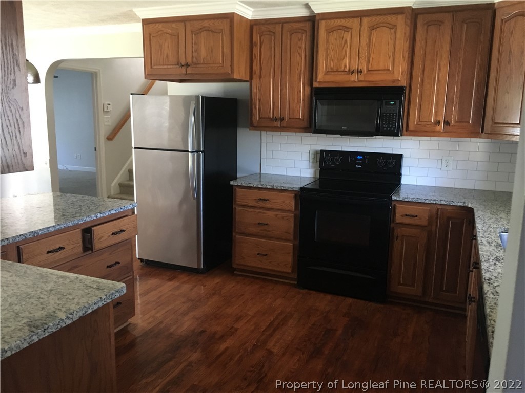 1409 Blue Ribbon Lane Hope Mills, NC 28348 - Photo 6 of 19 a kitchen with granite countertop a refrigerator stove and microwave