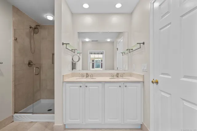 a bathroom with a granite countertop sink a mirror and shower
