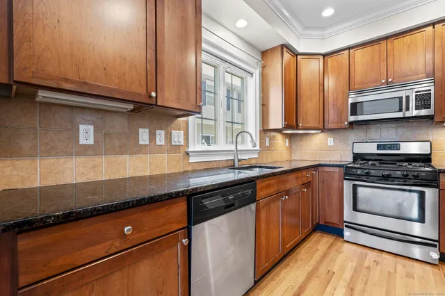 a kitchen with stainless steel appliances granite countertop a sink a stove and a microwave