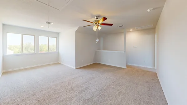 an empty room with windows and ceiling fan