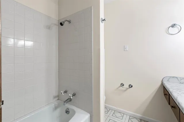 a bathroom with a tub shower vanity and a sink