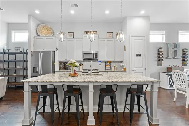 a kitchen with stainless steel appliances granite countertop a table chairs sink and cabinets