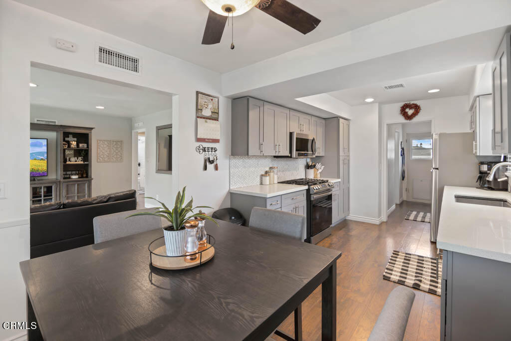 9195 Harvard Street Rancho Cucamonga, CA 91730 - Photo 16 of 37 a kitchen with stainless steel appliances kitchen island granite countertop a refrigerator a stove a sink a dining table and chairs with wooden floor