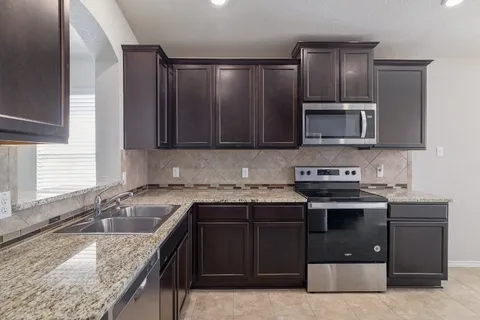 a kitchen with granite countertop a sink stove and microwave
