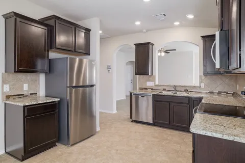 a kitchen with kitchen island granite countertop stainless steel appliances and refrigerator