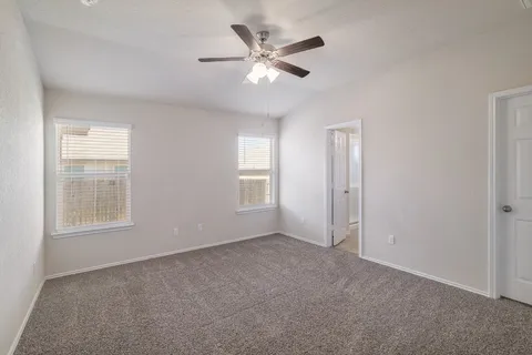 an empty room with chandelier fan and windows