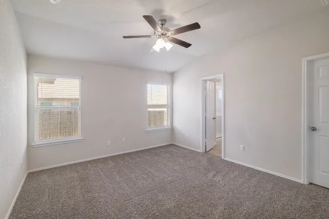 an empty room with chandelier fan and windows