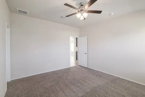 an empty room with a fan & a ceiling fan
