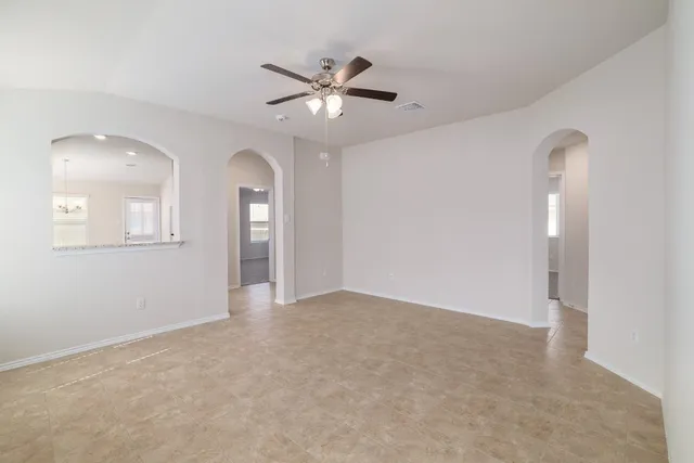 an empty room with chandelier fan and windows