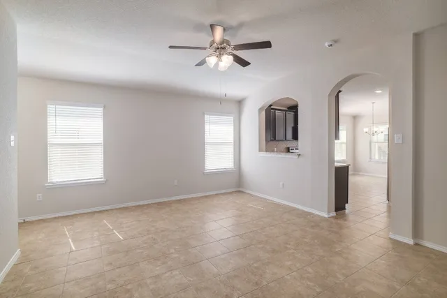 an empty room with windows and ceiling fan