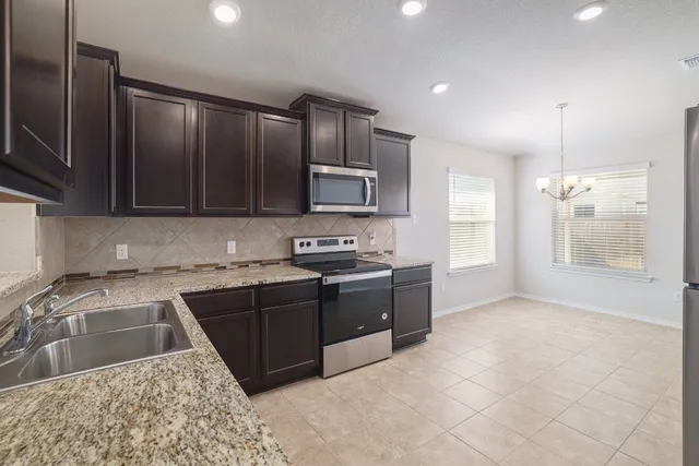 a kitchen with stainless steel appliances granite countertop a stove a sink and a microwave