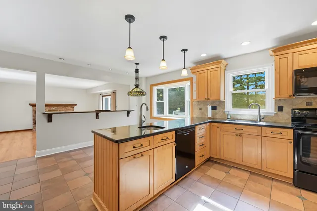 a kitchen with kitchen island granite countertop stainless steel appliances a sink counter top space cabinets and a window