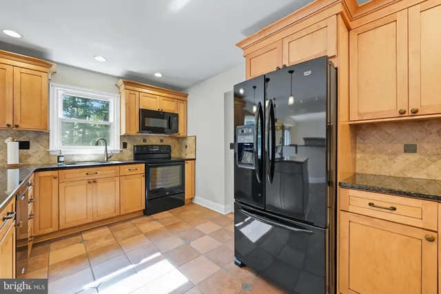 a kitchen with granite countertop a refrigerator a sink a stove and cabinets