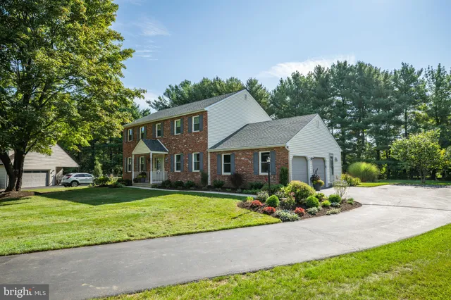 a front view of a house with a garden and trees