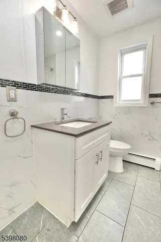 a bathroom with a granite countertop sink a toilet and a mirror