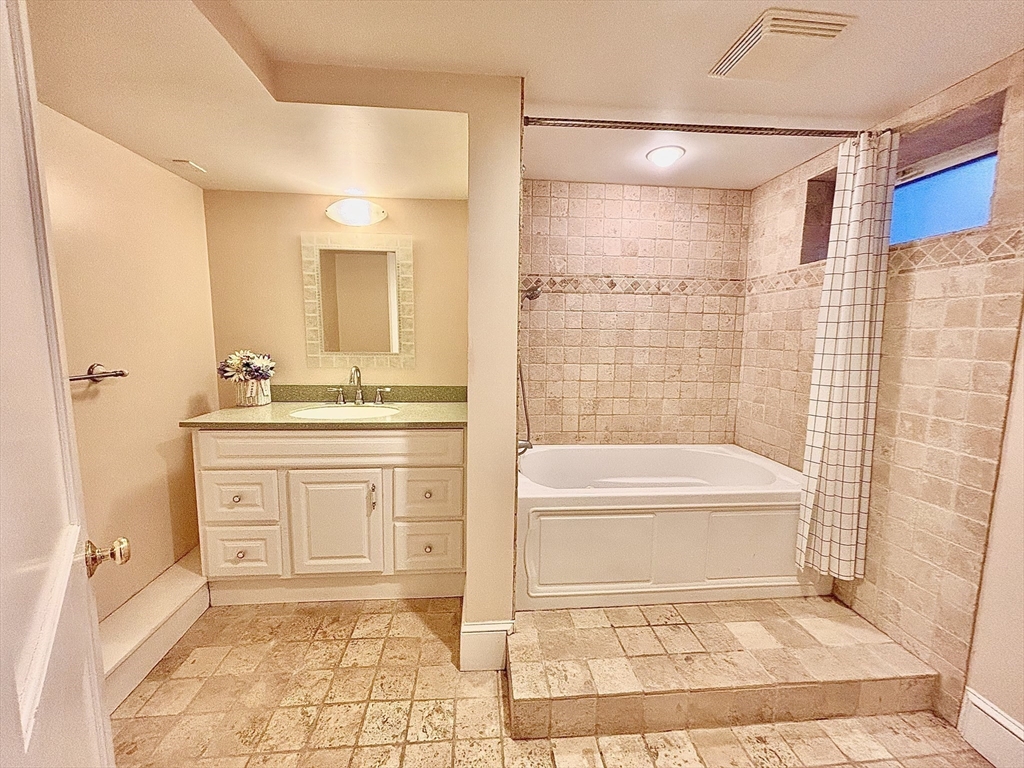 11 Sessions Street Wellesley, MA 02482 - Photo 18 of 22 a bathroom with a granite countertop sink a mirror a bathtub and a shower