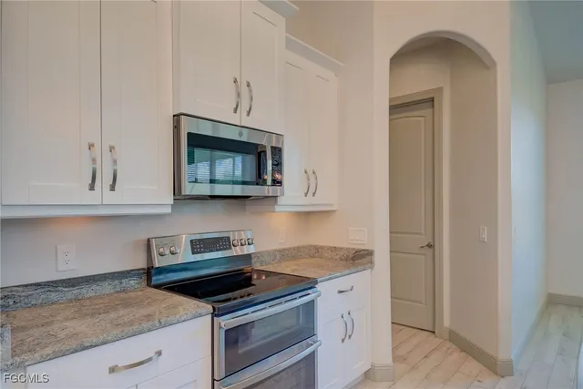 an empty room with chandelier fan and windows