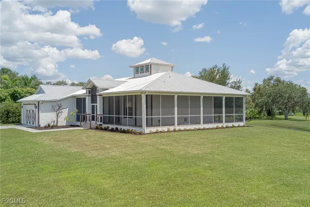 a view of a house with a big yard and large trees