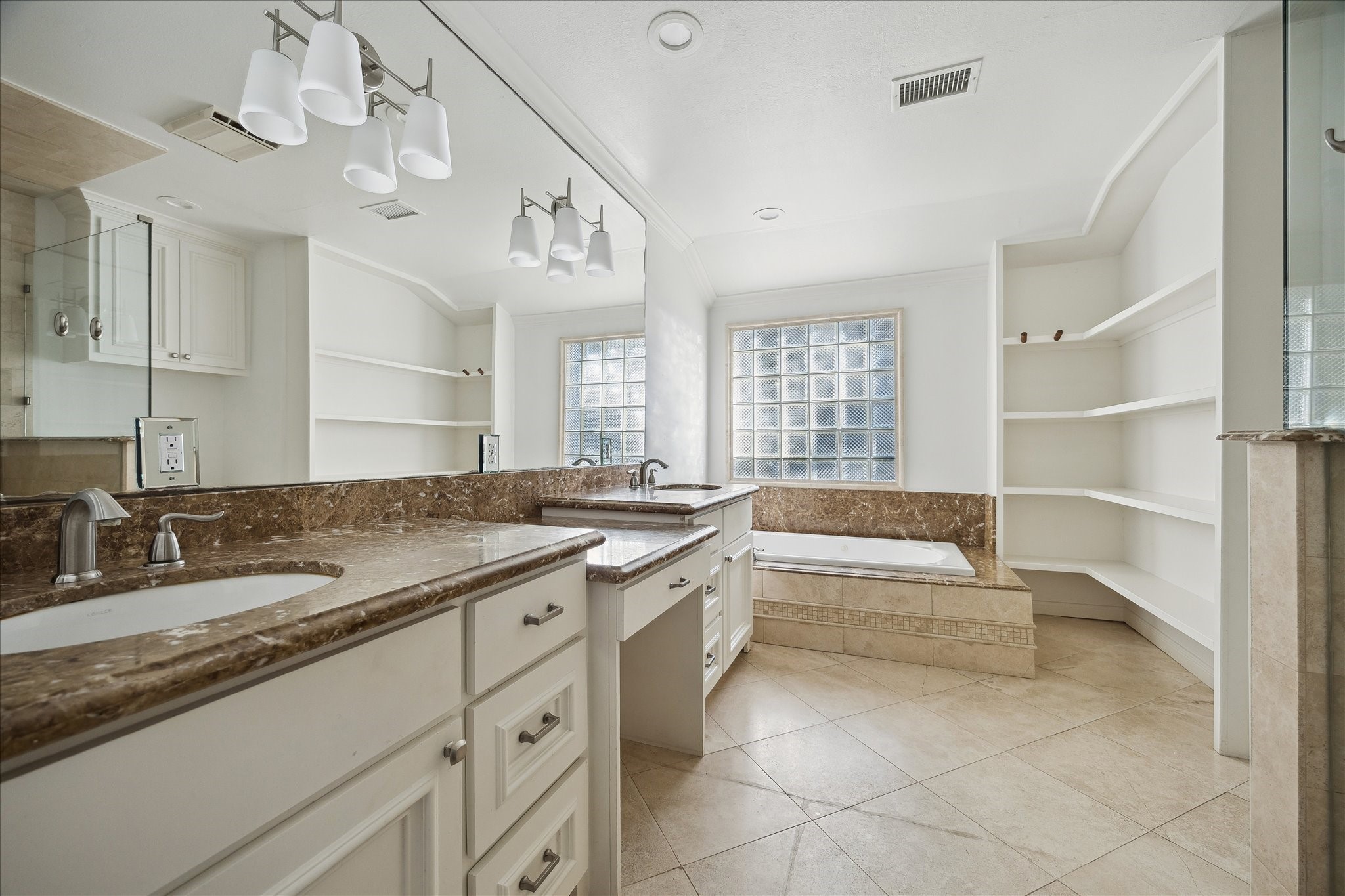 3049 Locke Lane Houston, TX 77019 - Photo 10 of 30 The primary bath showcases stunning marble countertops and travertine floors. The space features a vanity with custom built-ins and dual sinks. Natural light floods the space from oversized windows.