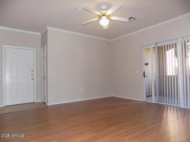an empty room with wooden floor fan and windows
