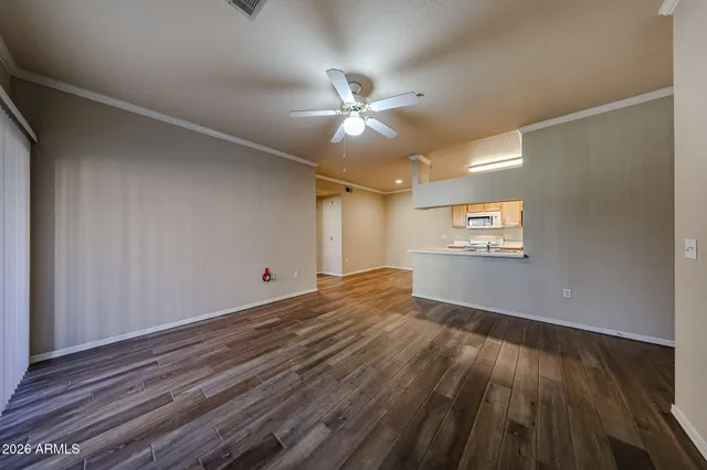 a view of kitchen and empty room with wooden floor