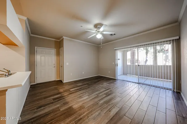 a view of an empty room with wooden floor and a ceiling fan