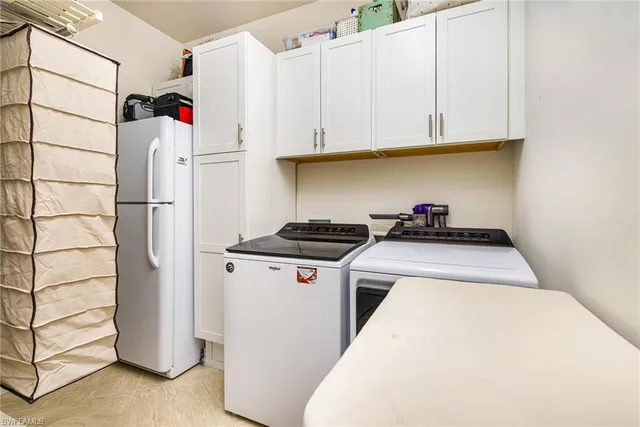 a utility room with refrigerator and cabinets