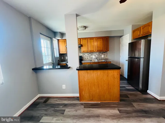 a view of a refrigerator in kitchen and an empty room