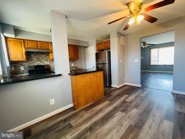a view of a kitchen with wooden floor and a ceiling fan