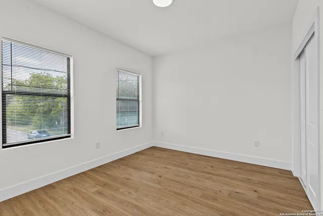 a view of an empty room with wooden floor and a window
